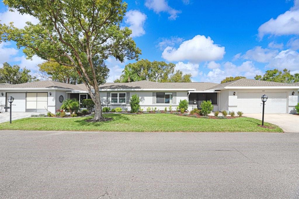 A single-story house with a light gray exterior, two garages, and a large front lawn — 1409 INGRAM DRIVE UNIT 75, SUN CITY CENTER, FL