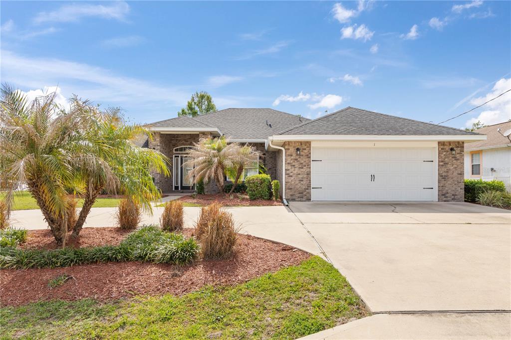 A single-story house with a brick facade, a two-car garage, and a palm tree — 1 PHEASANT DRIVE, PALM COAST, FL