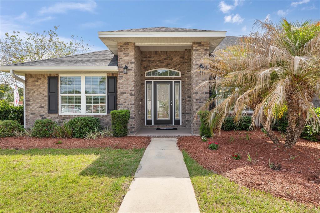 A brick-front house features a central entryway with a glass door and a concrete walkway — 1 PHEASANT DRIVE, PALM COAST, FL