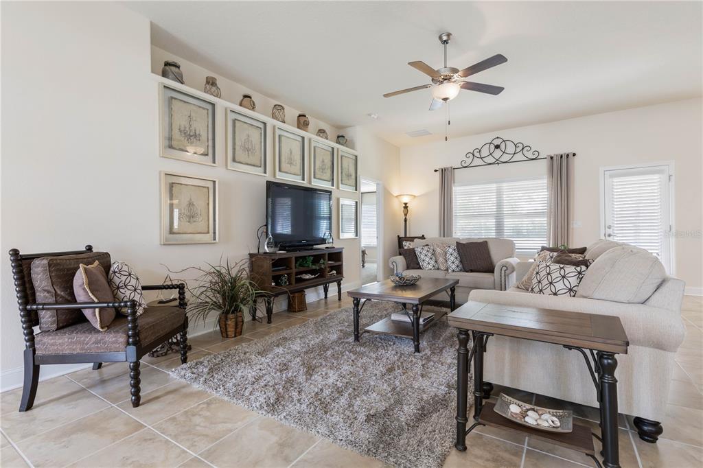 A living room features tile flooring, a shaggy rug, a ceiling fan, and framed artwork — 1 PHEASANT DRIVE, PALM COAST, FL