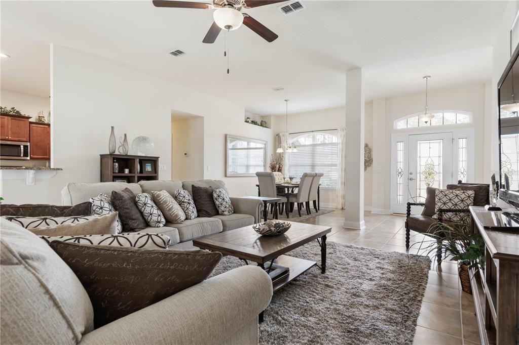 A living room with a beige sofa, coffee table, and dining area near the front entrance — 1 PHEASANT DRIVE, PALM COAST, FL