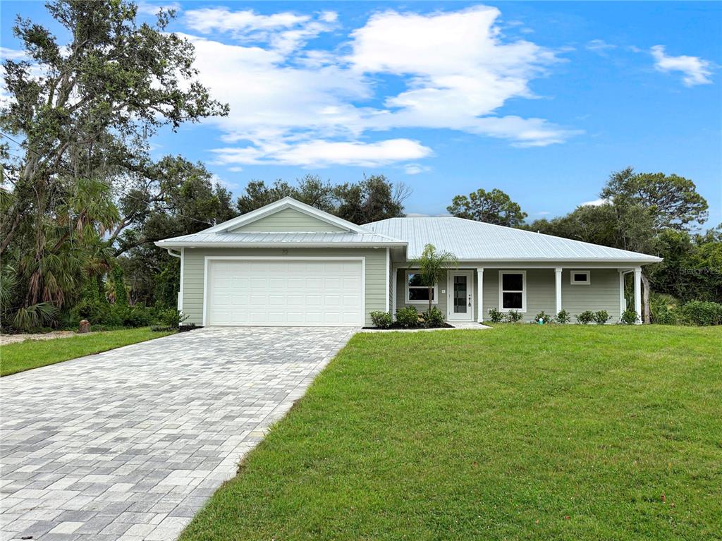 A single-story house with light green siding, a metal roof, and a paved driveway — 32 PURCELL STREET, PORT CHARLOTTE, FL