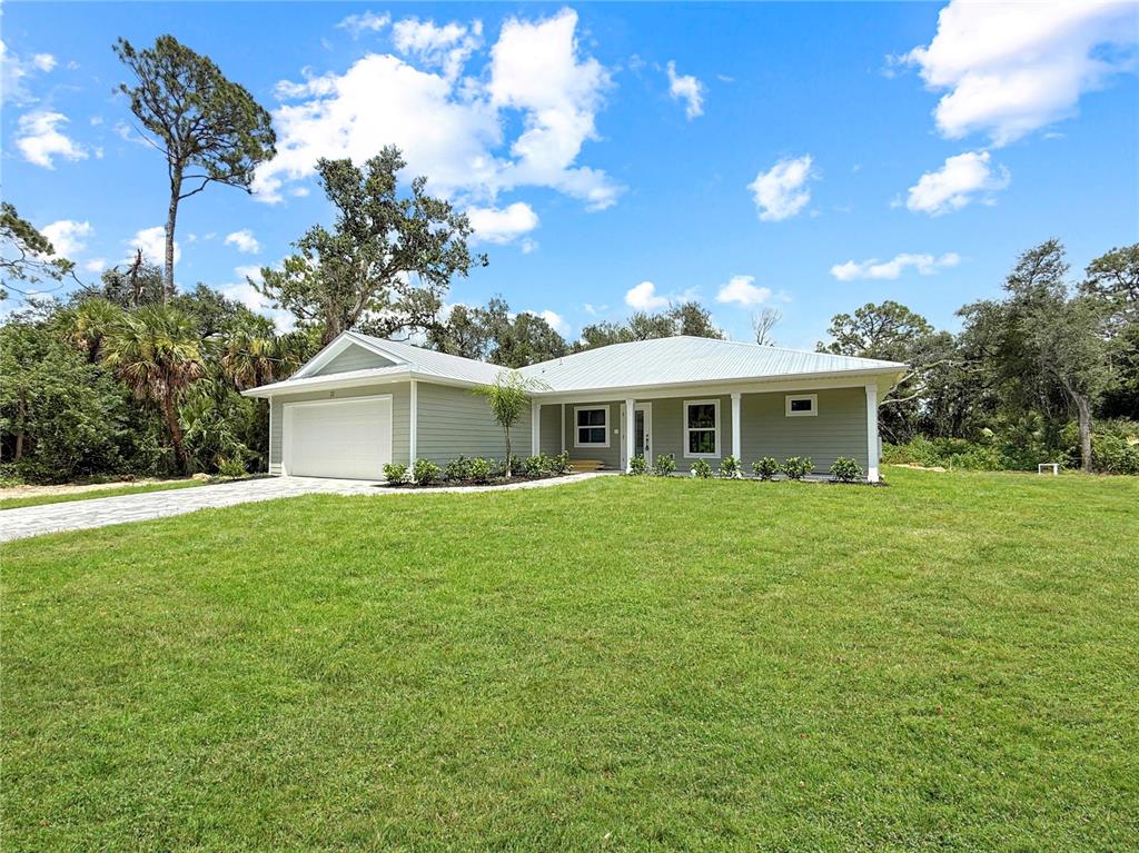 A single-story house with light green siding, a metal roof, and a two-car garage — 32 PURCELL STREET, PORT CHARLOTTE, FL