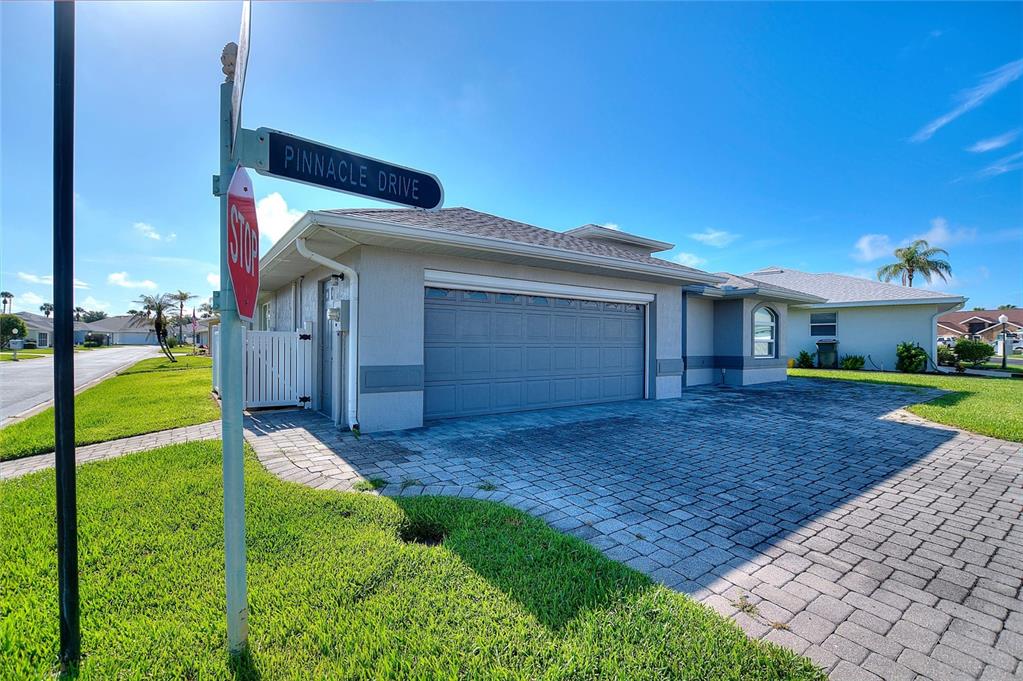 A street sign for Pinnacle Drive stands in front of a house with a garage — 704 PINNACLE DRIVE, HAINES CITY, FL