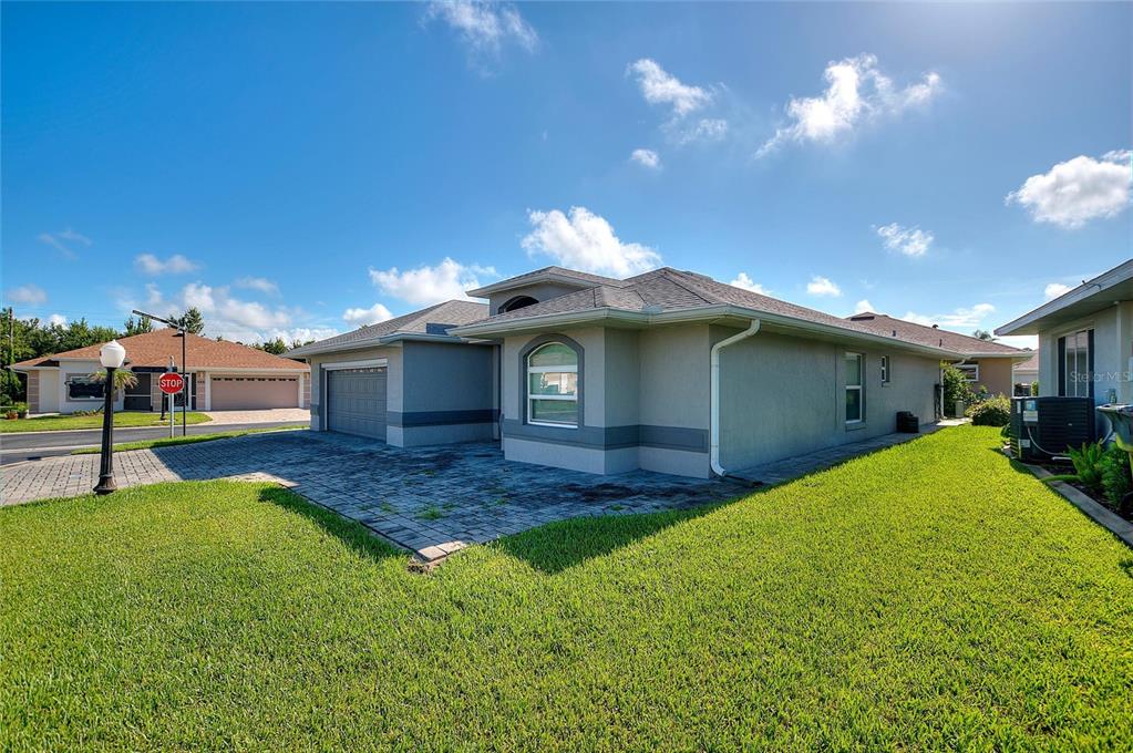 A single-story house with a gray stucco exterior, a paved driveway, and a green lawn — 704 PINNACLE DRIVE, HAINES CITY, FL