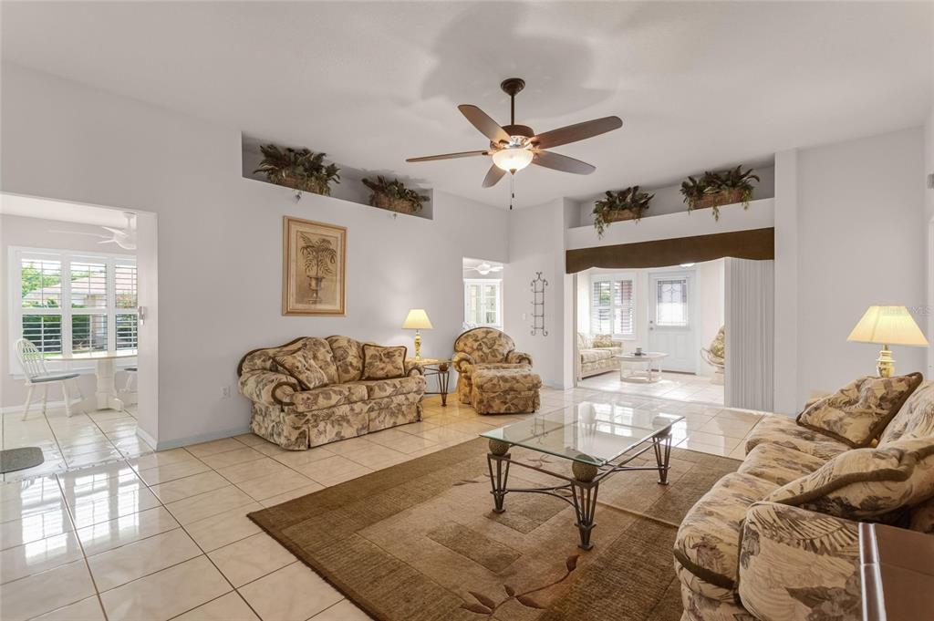 A living room with tile floors, a ceiling fan, and floral-patterned furniture — 704 PINNACLE DRIVE, HAINES CITY, FL