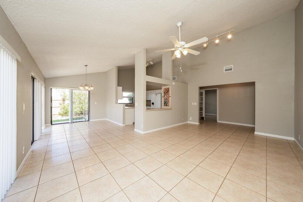 An open-concept living and dining area with vaulted ceilings, tile flooring, and a kitchen pass-through — BOYNTON BEACH, FL