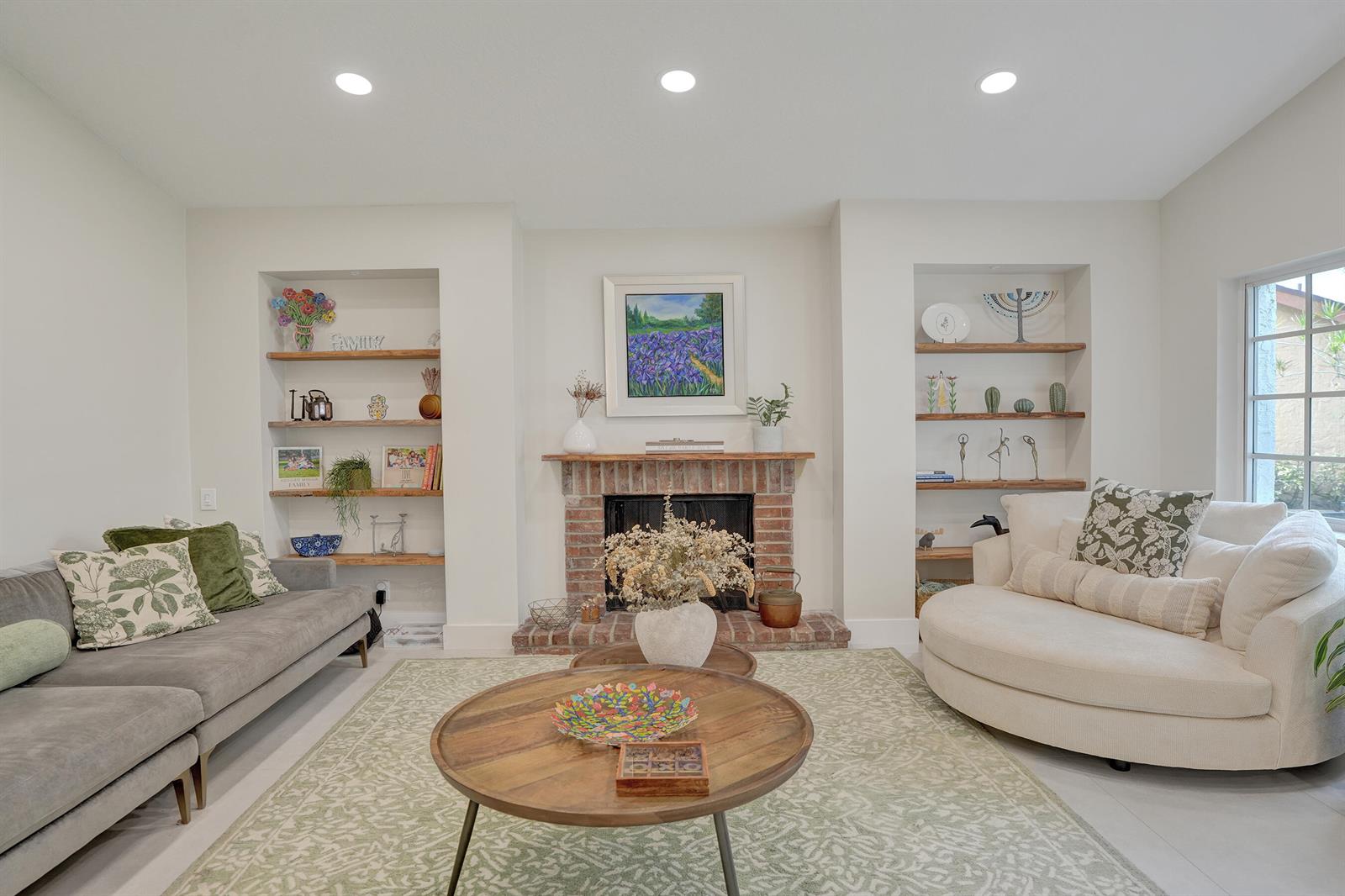 A living room features a brick fireplace, built-in wooden shelves, and a circular white sofa — 12213 Melissa Way, Cooper City FL 33026, COOPER CITY, FL