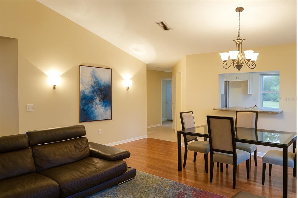 A living and dining area with hardwood floors, a dark leather sofa, and a chandelier — 10906 W COVE HARBOR DRIVE UNIT 10906, CRYSTAL RIVER, FL