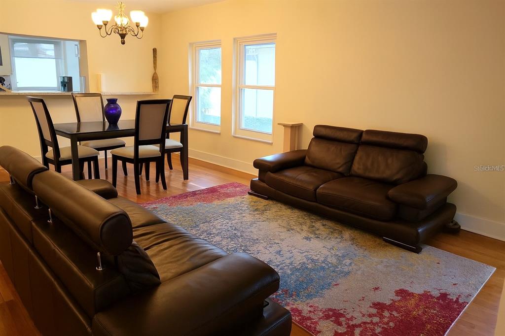 A living and dining area features dark leather sofas, a colorful rug, and hardwood floors — 10906 W COVE HARBOR DRIVE UNIT 10906, CRYSTAL RIVER, FL
