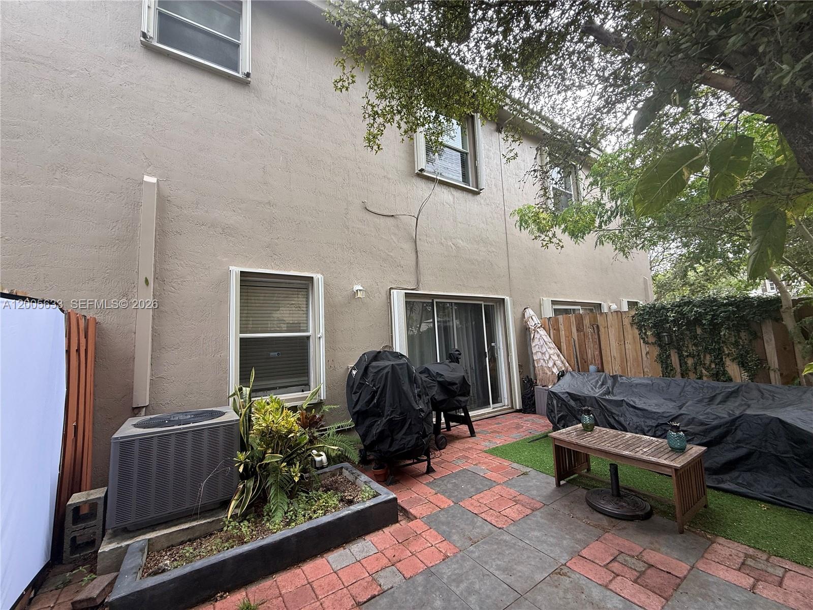 A backyard patio features a paved area, a planter box, an AC unit, and outdoor furniture — 8979 SW 225th St, Cutler Bay FL 33190, CUTLER BAY, FL