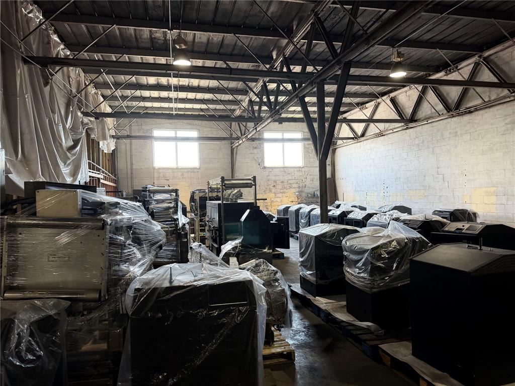 An industrial warehouse space filled with various pieces of machinery wrapped in clear plastic — 4320 S MANHATTAN AVENUE, TAMPA, FL