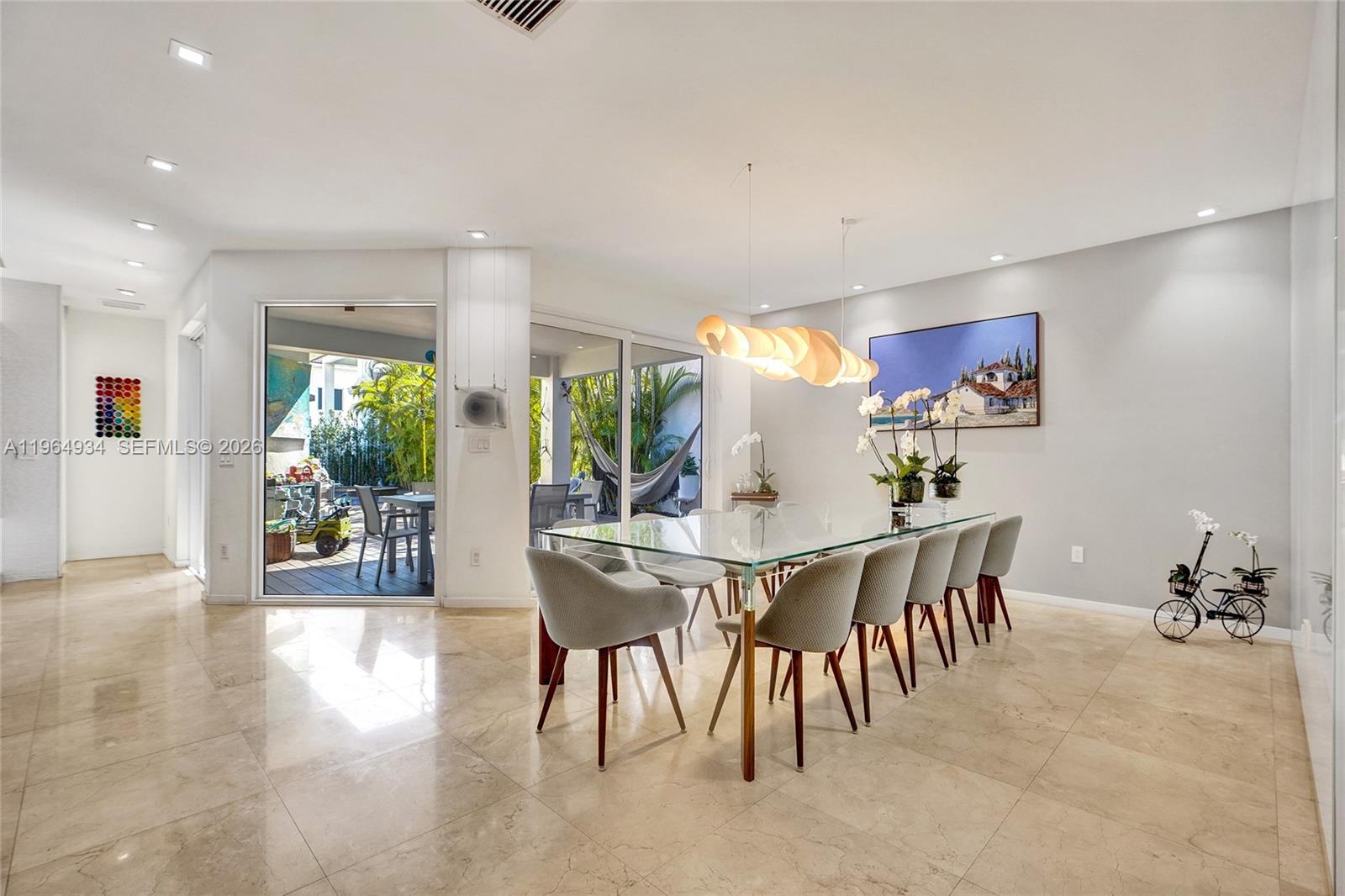 A dining room features a glass table, gray chairs, tile flooring, and sliding glass doors — 1662 Diplomat Dr, Miami FL 33179, MIAMI, FL