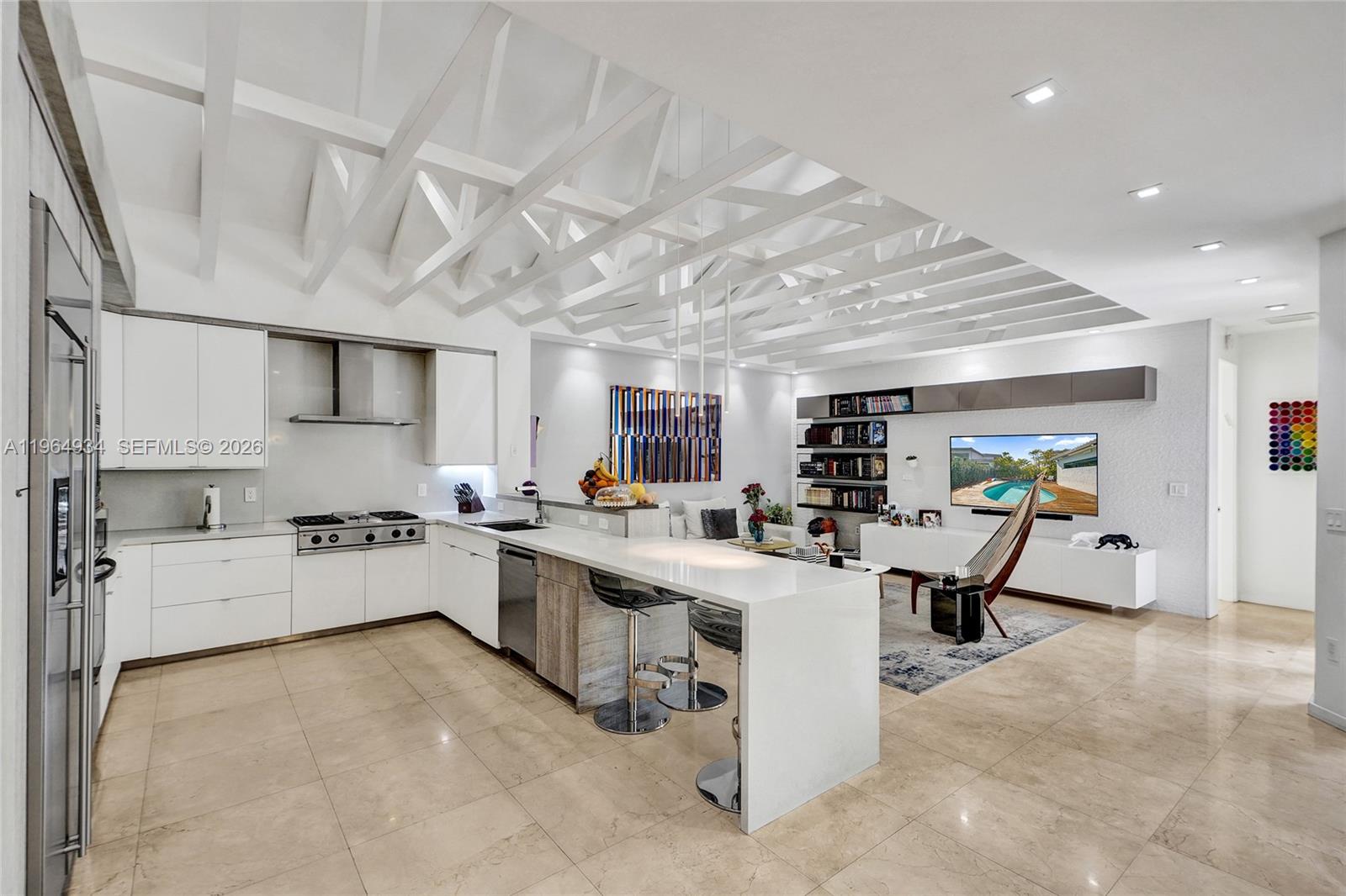A modern open-concept kitchen and living area features white cabinetry, a breakfast bar, and coffered ceilings — 1662 Diplomat Dr, Miami FL 33179, MIAMI, FL