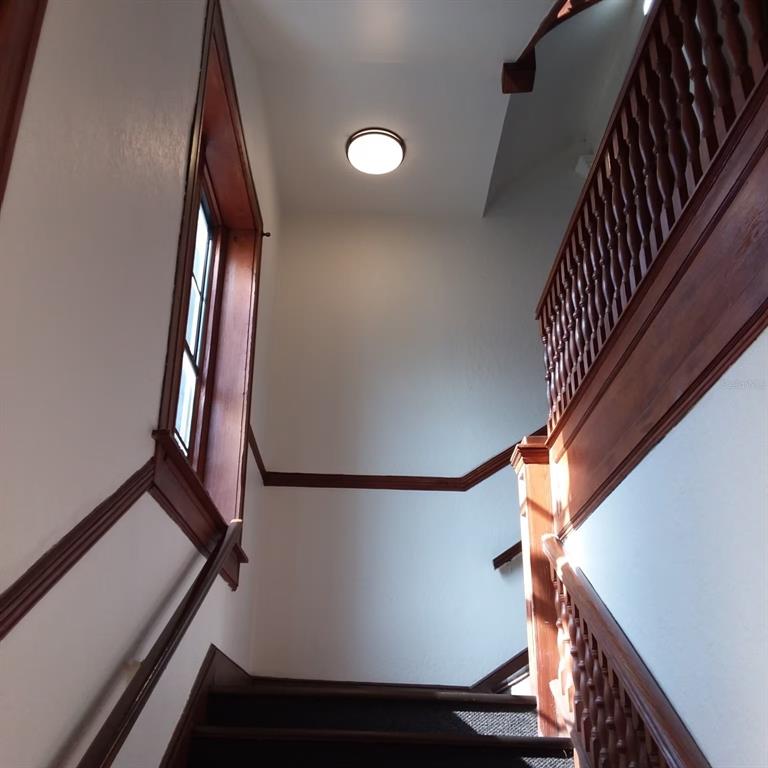 A staircase with dark wood railings and trim leads upward past a window — 44 SE 1ST AVENUE, OCALA, FL