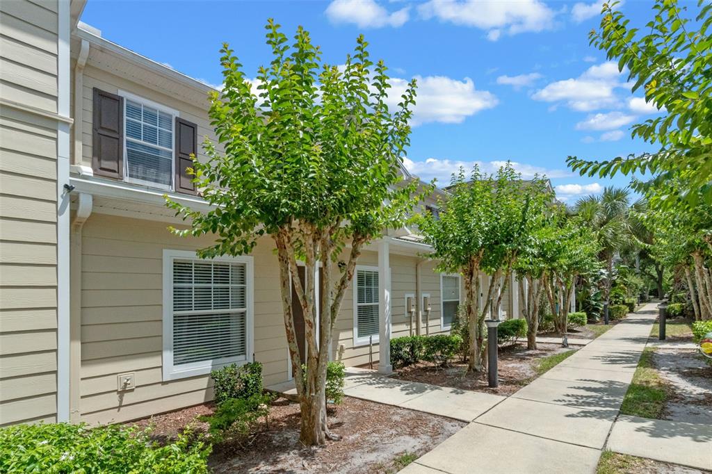 A two-story tan townhouse exterior features brown shutters, a sidewalk, and several small trees — 2952 LUCAYAN HARBOUR CIRCLE UNIT 106, KISSIMMEE, FL