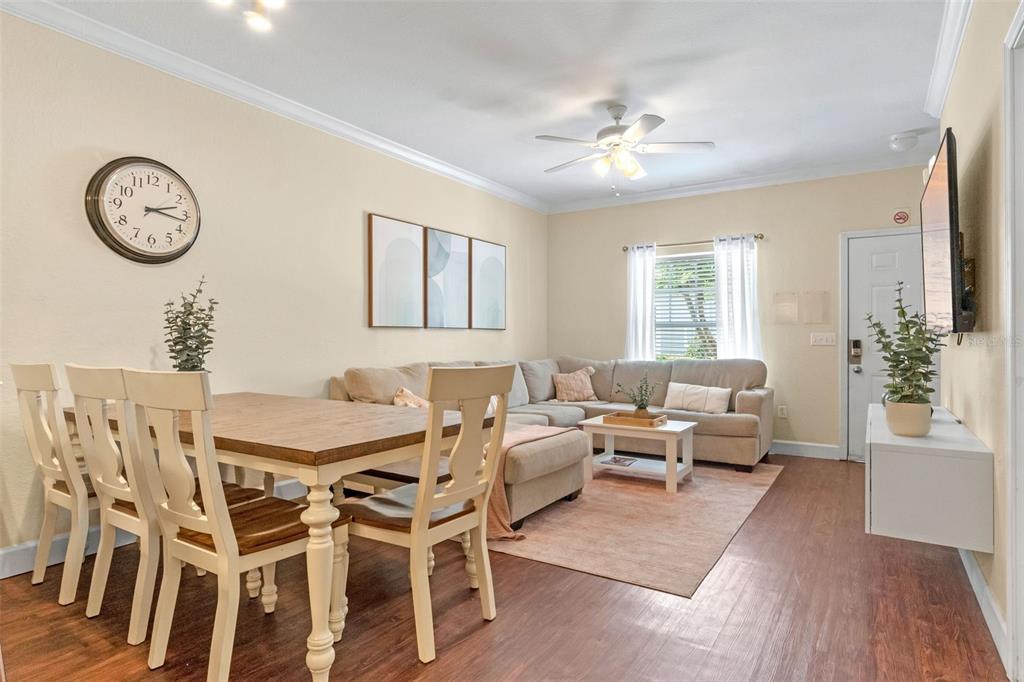 A dining area with a wooden table and chairs sits adjacent to a living room — 2952 LUCAYAN HARBOUR CIRCLE UNIT 106, KISSIMMEE, FL