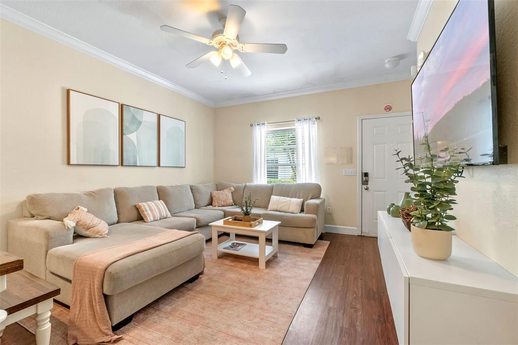 A living room features a large sectional sofa, a coffee table, and a wall-mounted television — 2952 LUCAYAN HARBOUR CIRCLE UNIT 106, KISSIMMEE, FL