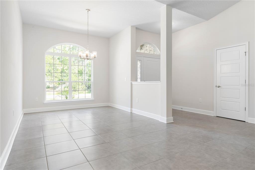 A dining room with gray tile floors, a chandelier, and a white door — 424 UNDERWOOD TRAIL, PALM COAST, FL