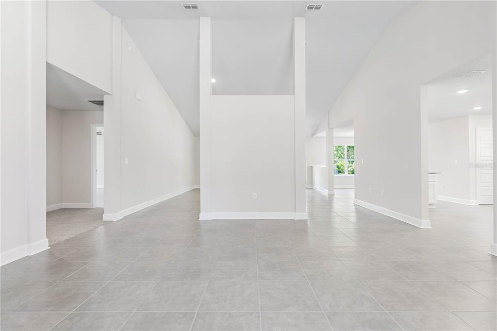 An open-concept living area features vaulted ceilings, light gray tile flooring, and white walls — 424 UNDERWOOD TRAIL, PALM COAST, FL