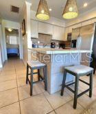 A kitchen features a breakfast bar with two stools, pendant lighting, and stainless steel appliances — 525 MANATEE COURT UNIT 13, VENICE, FL