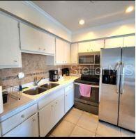A kitchen with white cabinets, stainless steel appliances, and a double sink with tiled backsplash — 525 MANATEE COURT UNIT 13, VENICE, FL