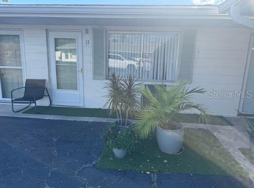 The exterior of a white residential unit features a front door, a window, and potted plants — 525 MANATEE COURT UNIT 13, VENICE, FL