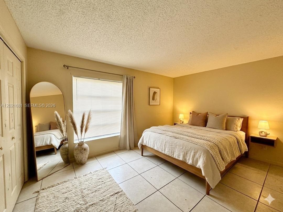 A bedroom features a bed, a floor mirror, a window with curtains, and tile flooring — 17650 NW 68th Ave # A2005, Hialeah FL 33015, HIALEAH, FL