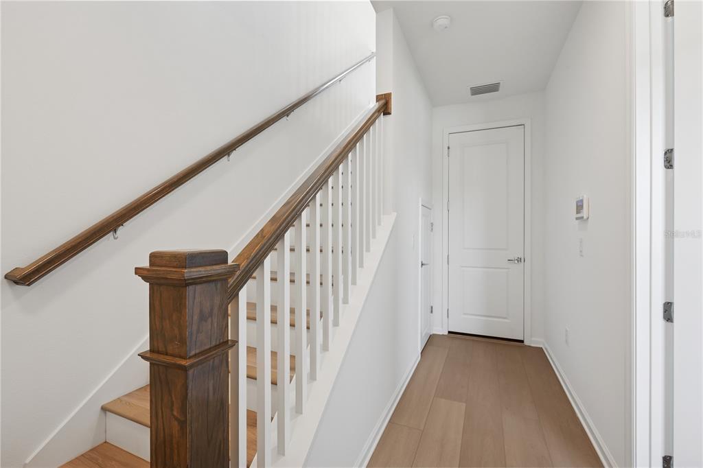 A hallway features light wood flooring, a white door, and a staircase with wooden railings — 9168 SINATRA LANE, ORLANDO, FL