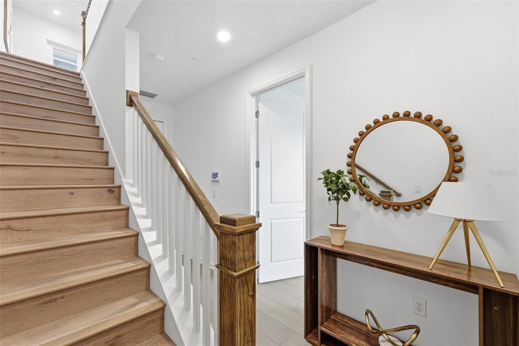A staircase with wooden treads and a white railing stands beside a console table — 9168 SINATRA LANE, ORLANDO, FL