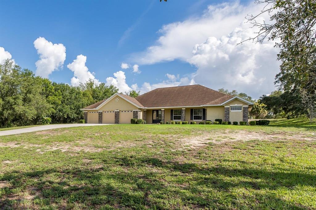 A single-story house with a three-car garage and a large front lawn — 343 ROYAL PALM WAY, SPRING HILL, FL
