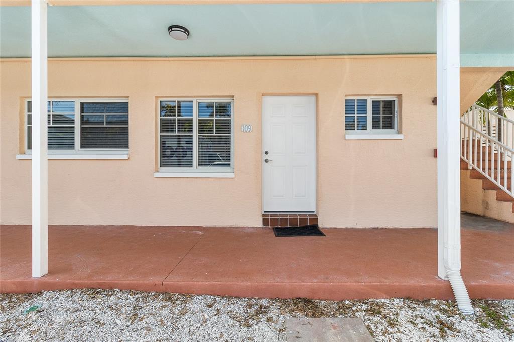 The exterior of a peach-colored building features a white door labeled 109 and windows — 19417 GULF BOULEVARD UNIT C109, INDIAN ROCKS BEACH, FL
