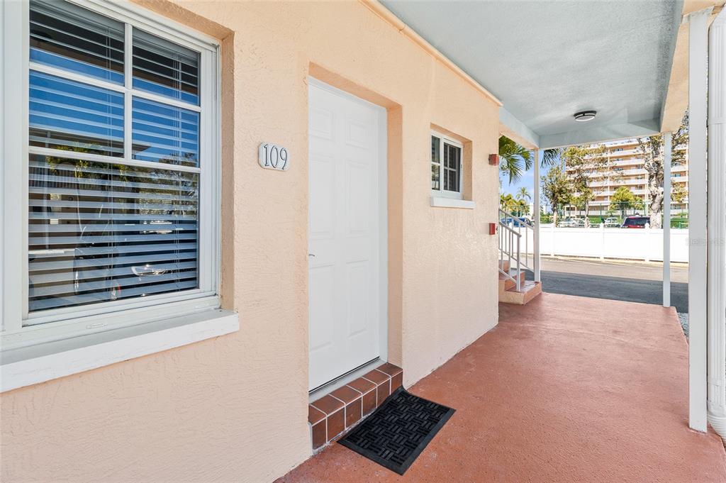 A peach-colored exterior wall features a white door labeled 109, a window, and a porch — 19417 GULF BOULEVARD UNIT C109, INDIAN ROCKS BEACH, FL