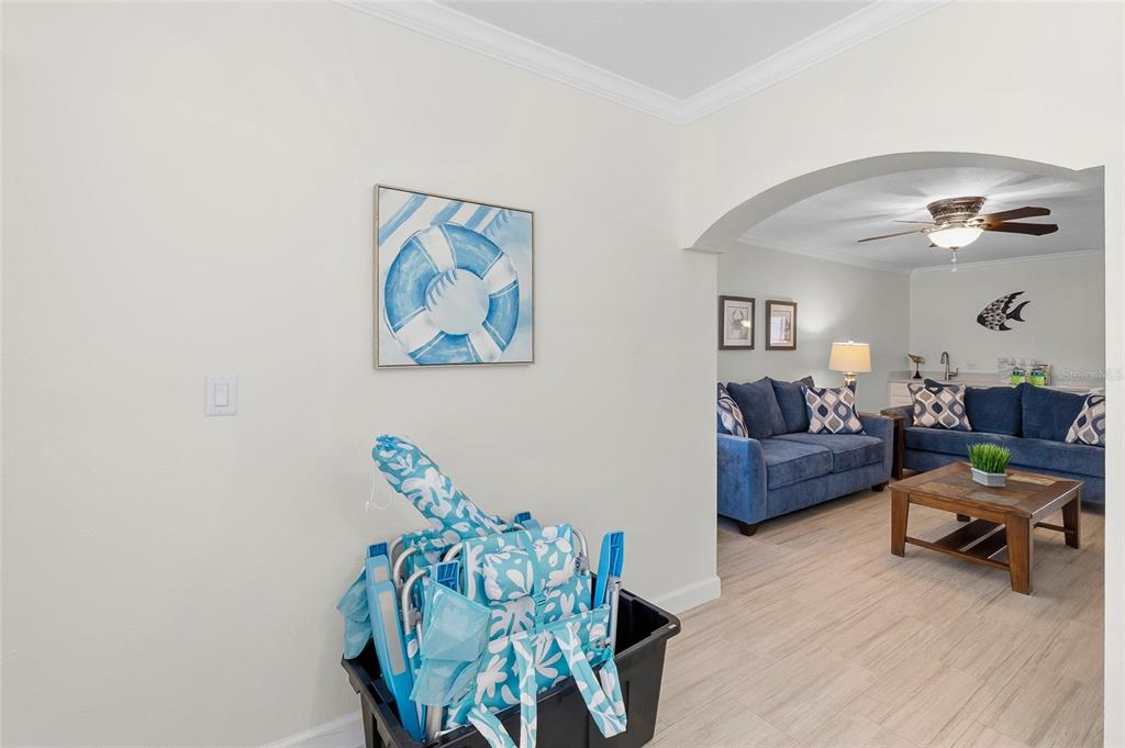 A living room with blue sofas is visible through an arched doorway from a hallway — 19417 GULF BOULEVARD UNIT C109, INDIAN ROCKS BEACH, FL