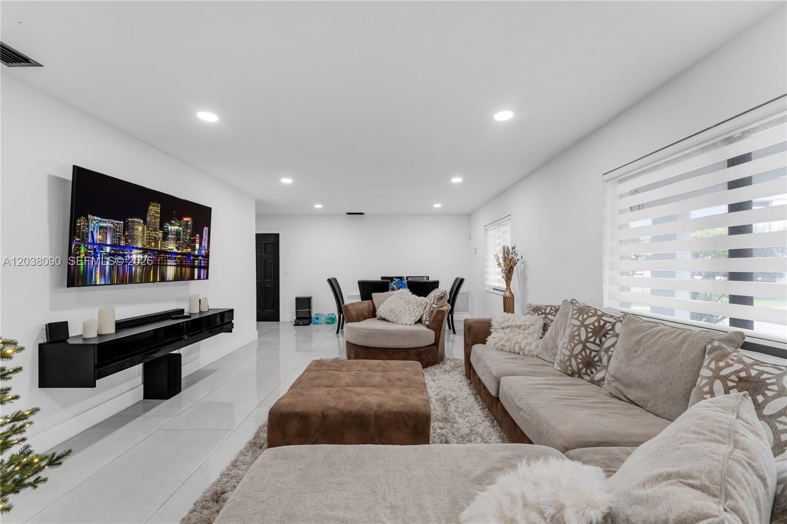A living room features a wall-mounted television, a sectional sofa, and white tile flooring — 551 SW 127th Ave, Miami FL 33184, MIAMI, FL