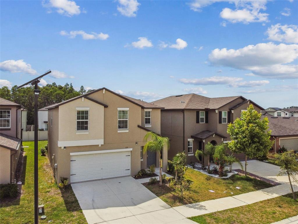 An exterior view of a two-story suburban house with a tan stucco facade and garage — 2139 STELLAR BRILLIANCE WAY, LUTZ, FL