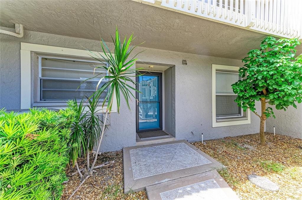 The exterior of a ground-floor unit features a front door, two windows, and landscaping — 5962 7TH AVE W, BRADENTON, FL