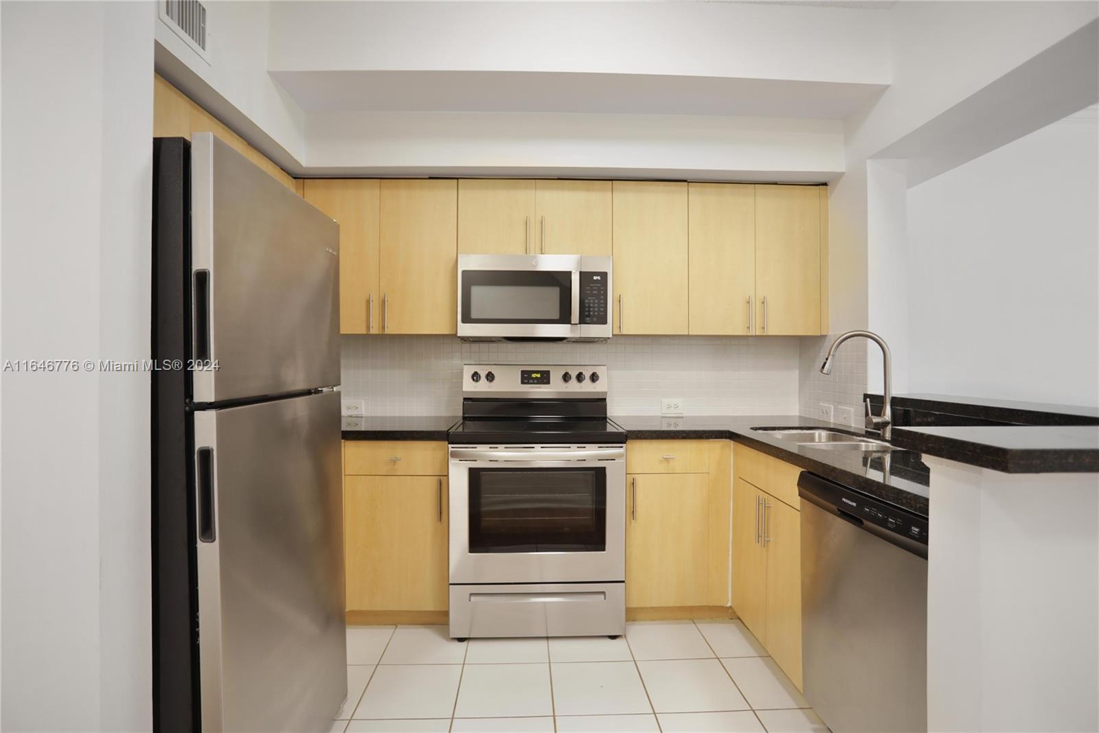 A kitchen features light wood cabinets, stainless steel appliances, and dark countertops — 2941 NE 185th St # 1305, Miami FL 33180, MIAMI, FL