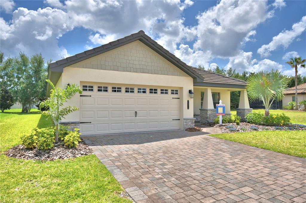 A single-story house with a beige stucco exterior, a two-car garage, and a paved driveway — 4970 TENNESSEE LAKE DRIVE, AUBURNDALE, FL