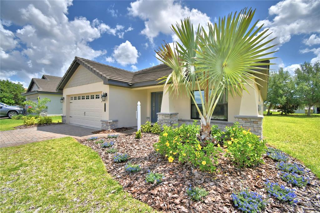 A single-story house with a tan stucco exterior, stone accents, and a palm tree in front — 4970 TENNESSEE LAKE DRIVE, AUBURNDALE, FL