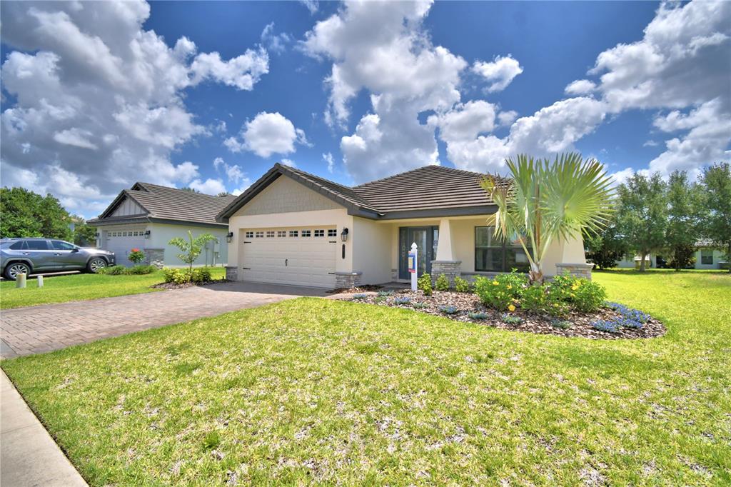 A single-story house with a two-car garage, stone accents, and a landscaped front yard — 4970 TENNESSEE LAKE DRIVE, AUBURNDALE, FL