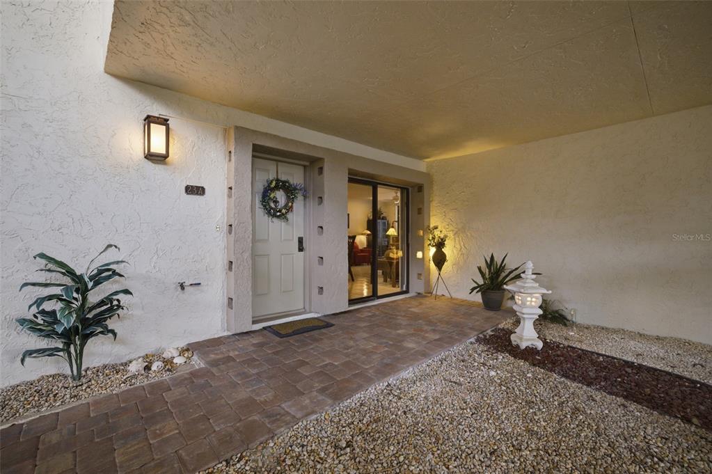 A covered entryway features a front door, sliding glass doors, and a stone-paved walkway — 3220 SOUTHSHORE DRIVE UNIT 23A, PUNTA GORDA, FL