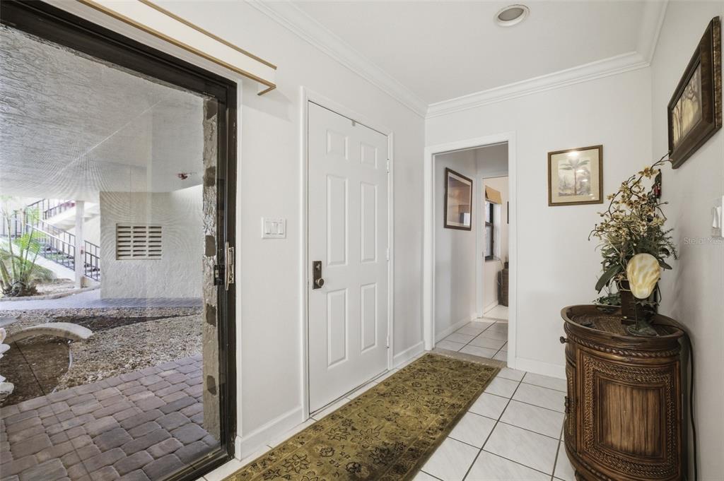 An entryway features a white door, tiled floors, a patterned runner, and a sliding glass door — 3220 SOUTHSHORE DRIVE UNIT 23A, PUNTA GORDA, FL