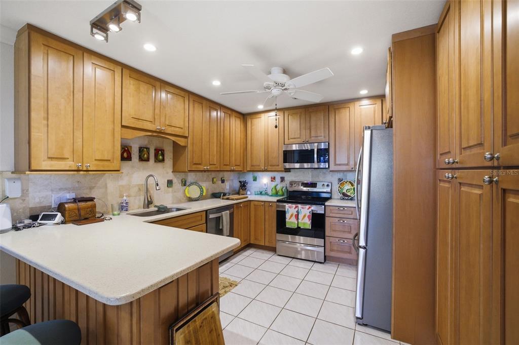 A kitchen features light wood cabinets, stainless steel appliances, and a white countertop peninsula — 3220 SOUTHSHORE DRIVE UNIT 23A, PUNTA GORDA, FL