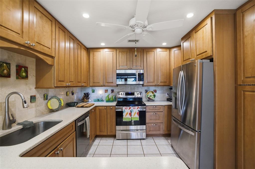 A kitchen features wood cabinets, stainless steel appliances, light countertops, and a tile floor — 3220 SOUTHSHORE DRIVE UNIT 23A, PUNTA GORDA, FL