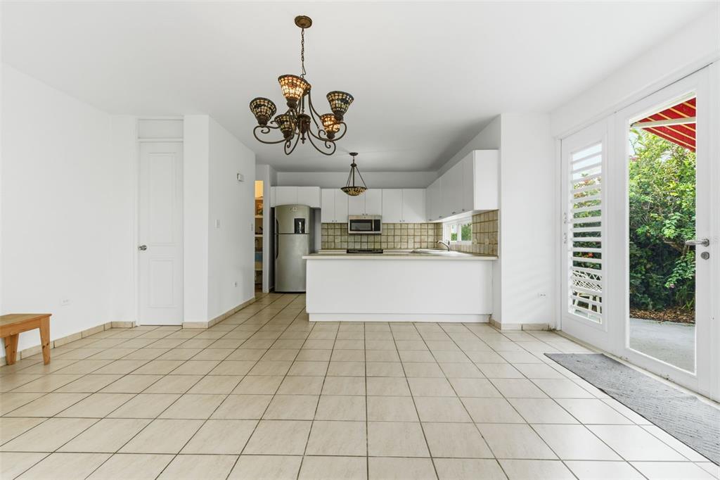 A kitchen with white cabinets and tile flooring opens to a patio through glass doors — B-6 VIA MORIZ ST. PASEO DEL MAR UNIT 434, DORADO, PR