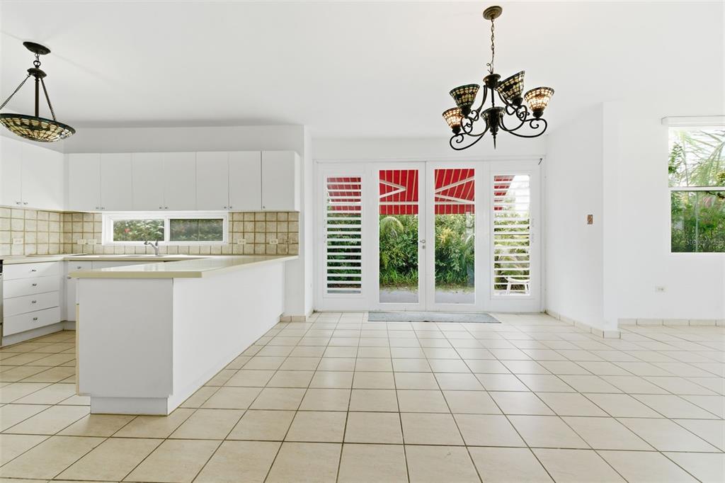 A kitchen and dining area with white cabinets, tile flooring, and glass doors to a patio — B-6 VIA MORIZ ST. PASEO DEL MAR UNIT 434, DORADO, PR
