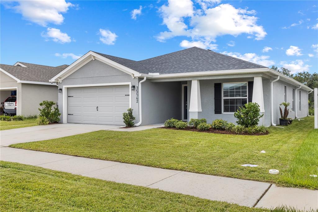 A single-story gray house with a two-car garage and a front porch — 35542 BELLINGTON BOULEVARD, ZEPHYRHILLS, FL