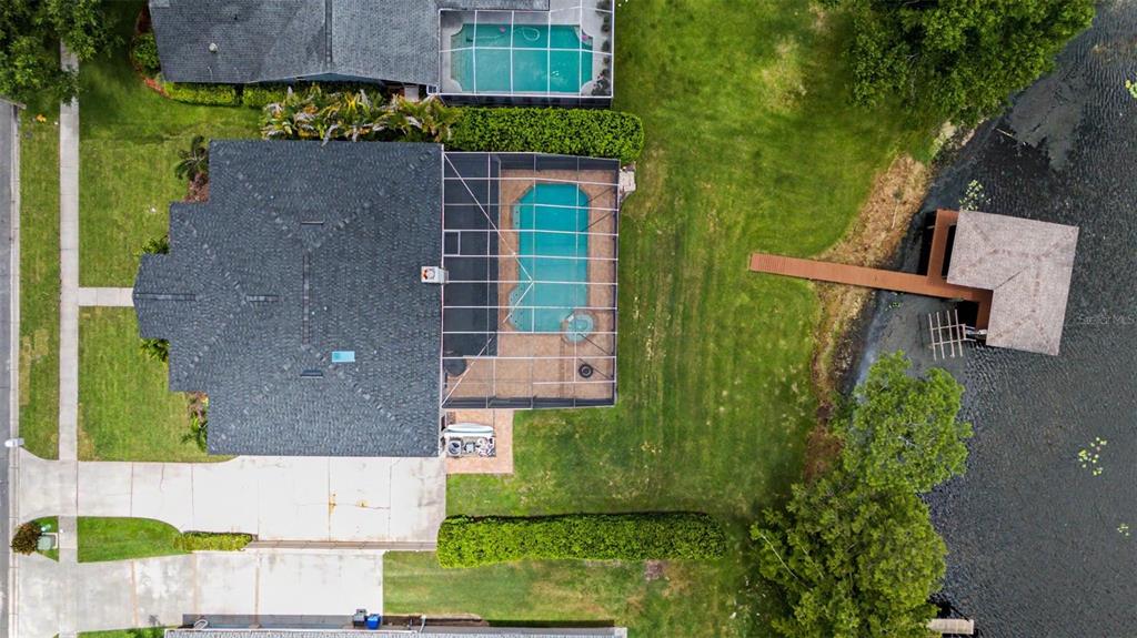 An aerial view shows a house with a screened pool, backyard, and private dock — 15004 MAURINE COVE LANE, ODESSA, FL