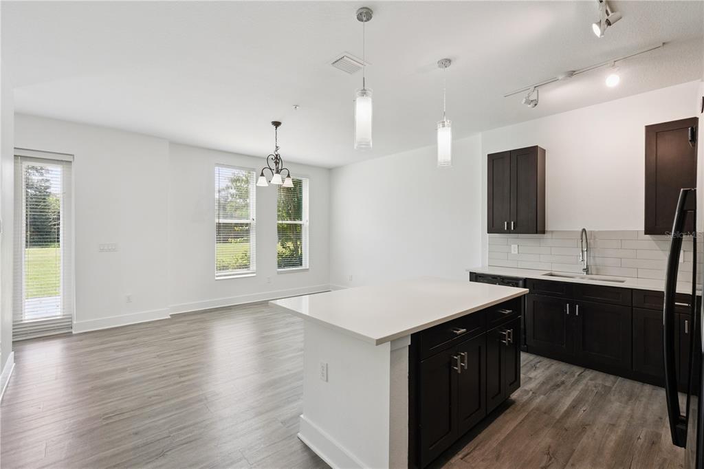 A kitchen and dining area with dark cabinets, a white island, and light wood flooring — 1841 HOUSTON STREET, KISSIMMEE, FL